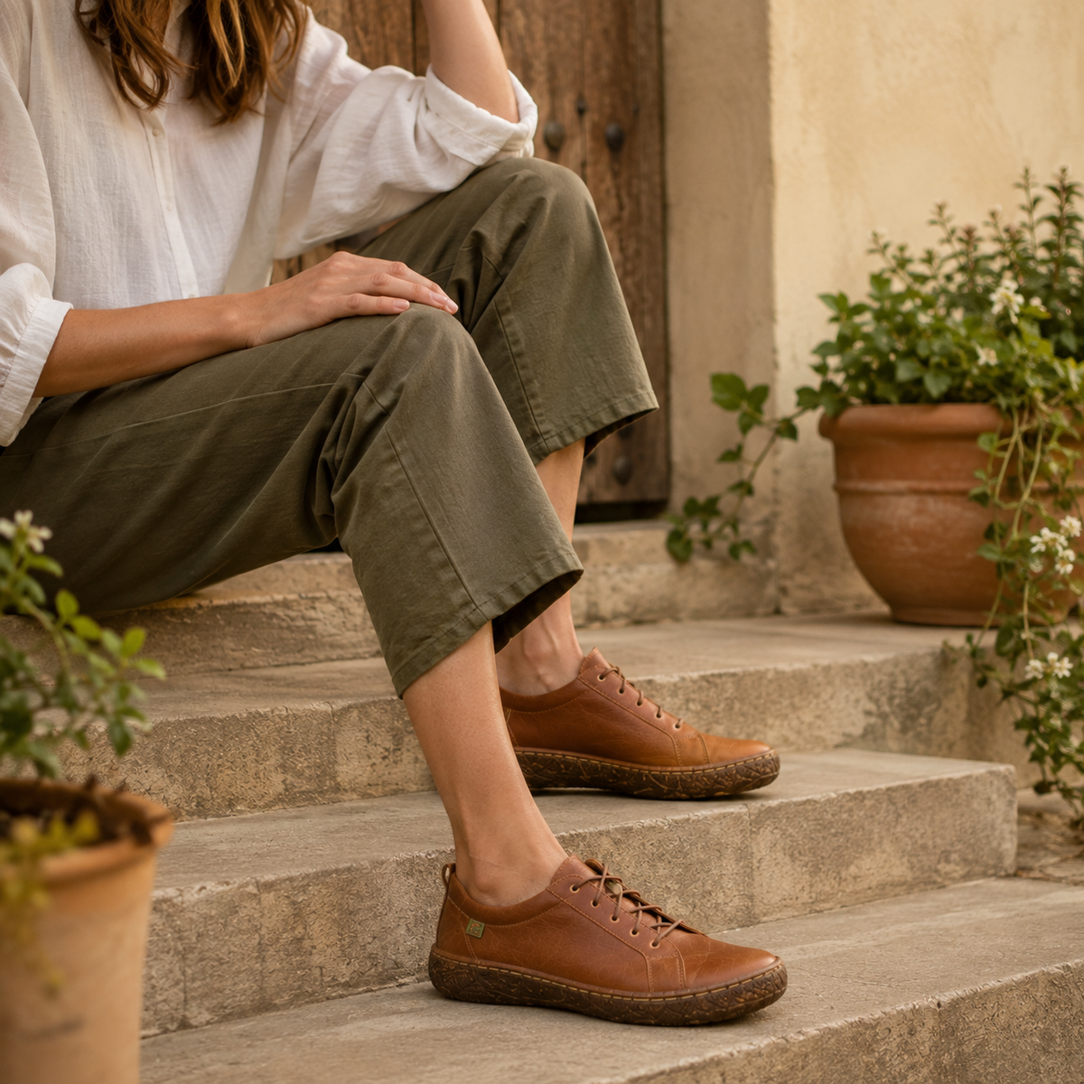 Frau mit klassischen braunen El Naturalista Lederschuhen auf Natursteinstufen – shoedeal.de